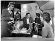 Pan Am flight attendants serving passengers on a Boeing 707, jet clipper
